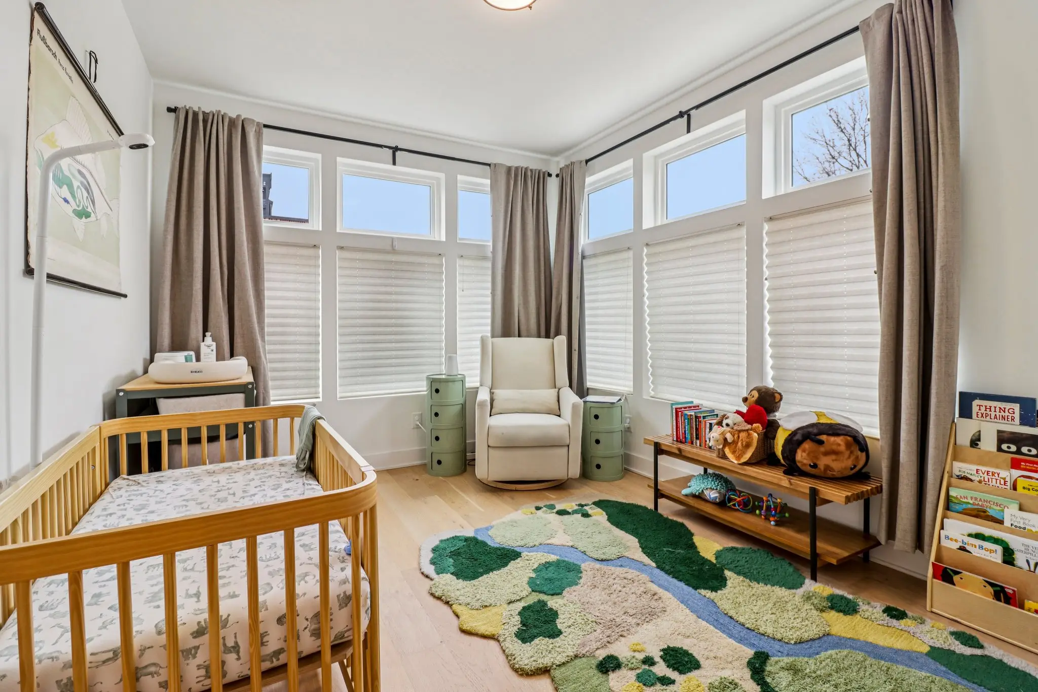 Bright corner bedroom with a bank of tall windows on two walls and light oak floors.
