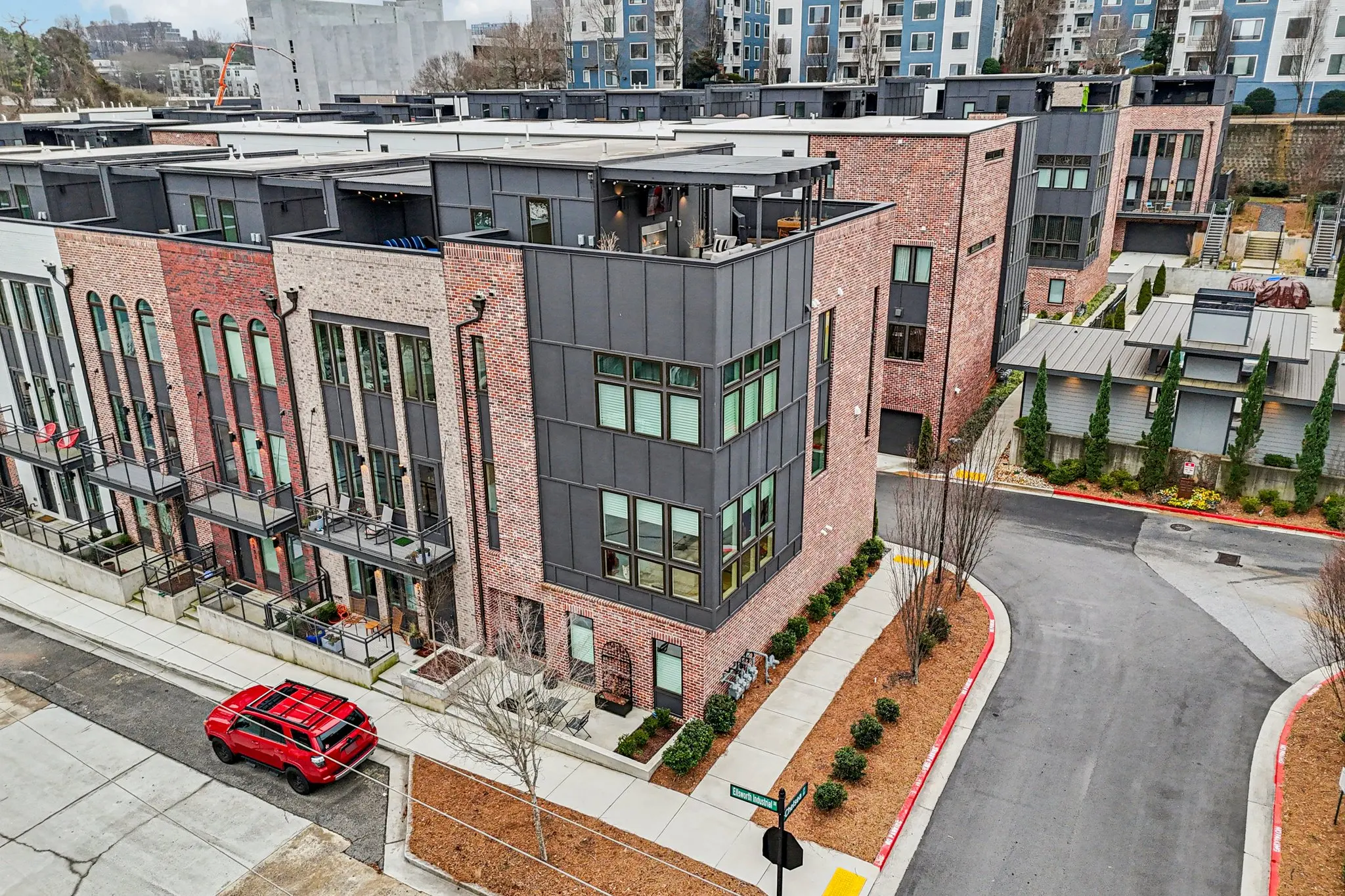 Aerial view of the four-level brick townhome and its rooftop terrace within the Chelsea Westside community.