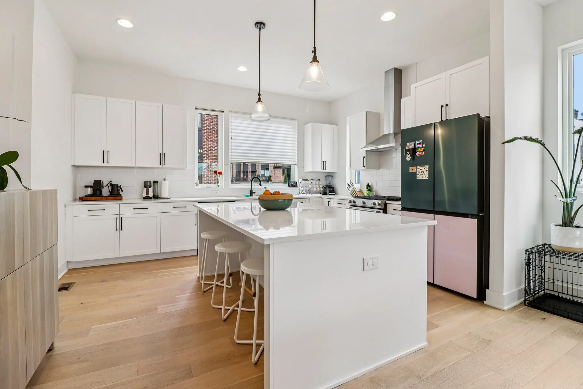 Kitchen with white shaker cabinetry, quartz counters, glass pendant lights and a waterfall-edge island.