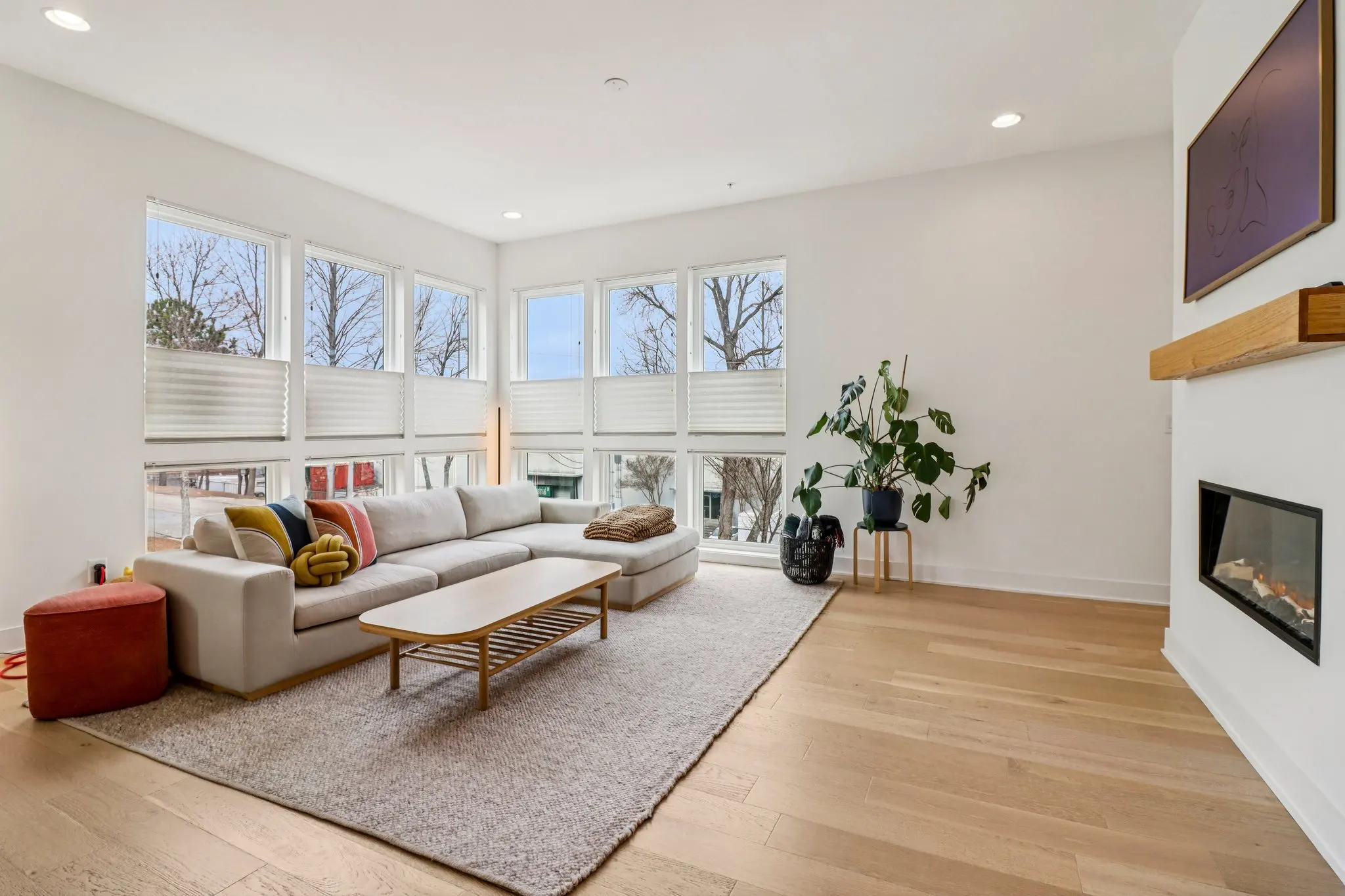 Living room with oversized corner windows and a transom band above, filling the room with daylight.