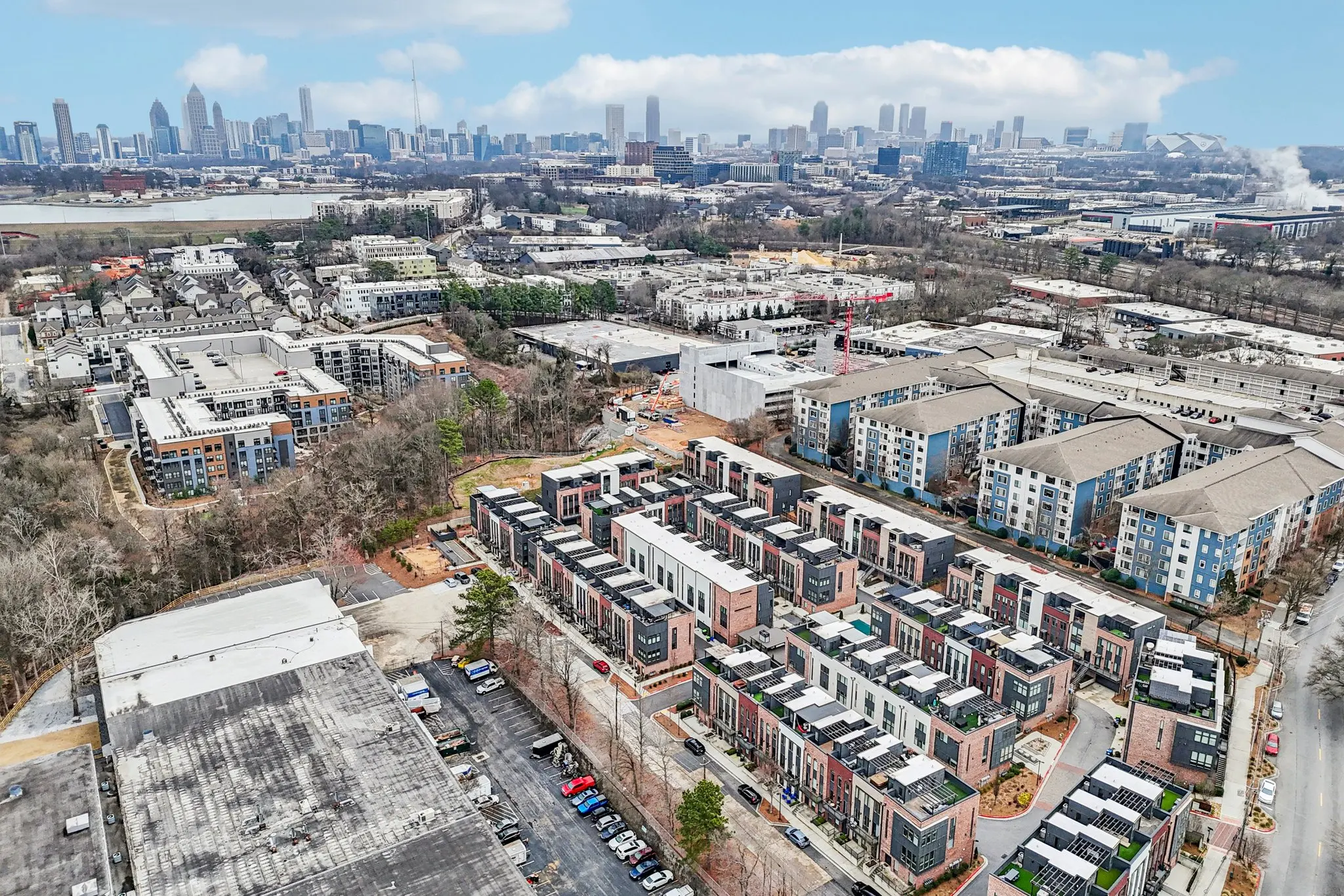 Aerial view over the Chelsea Westside community toward the downtown Atlanta skyline, with Upper Westside warehouses and mid-rise buildings between.