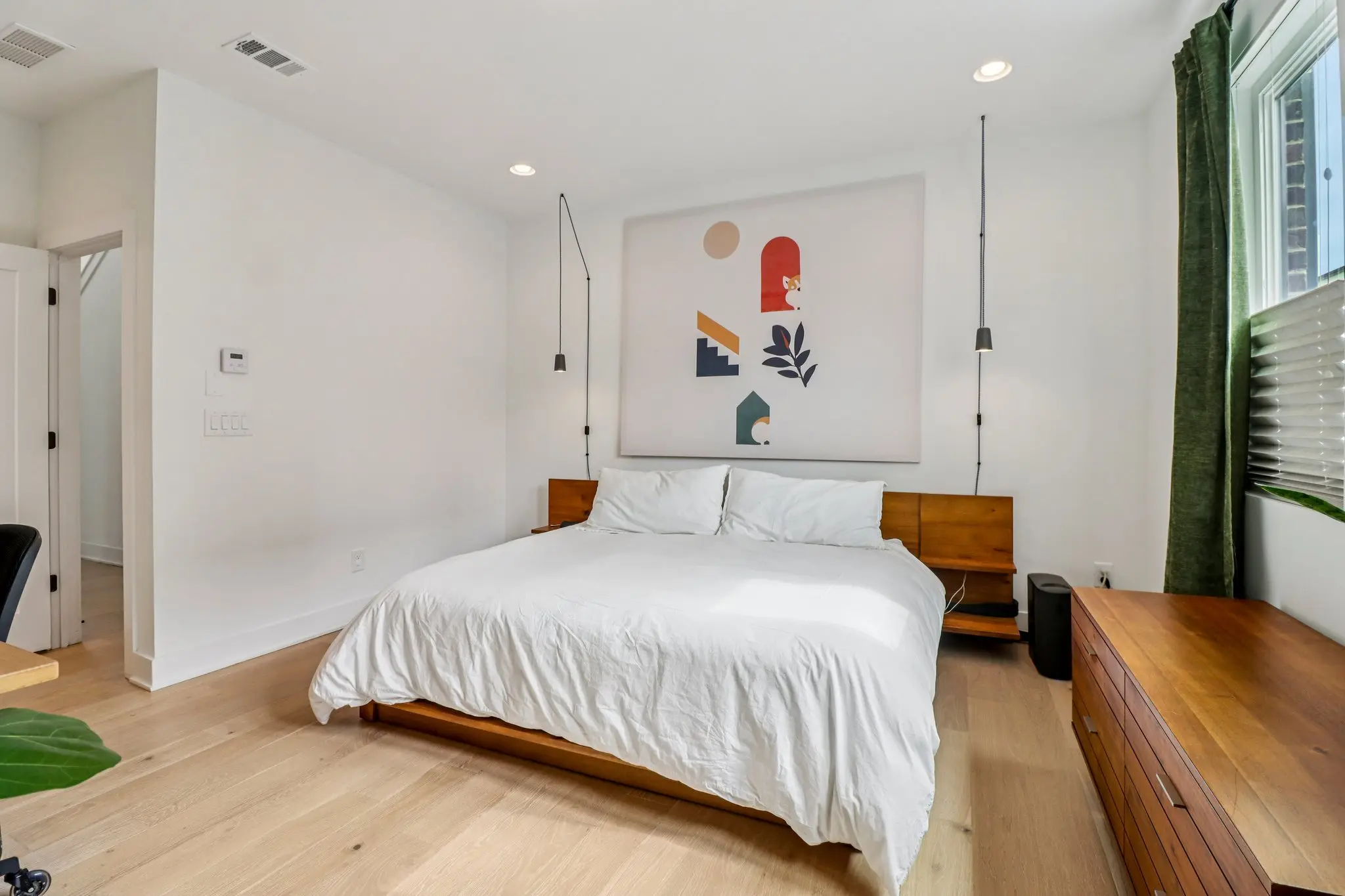 Primary bedroom with a wood platform bed, floating nightstands and pendant reading lights.